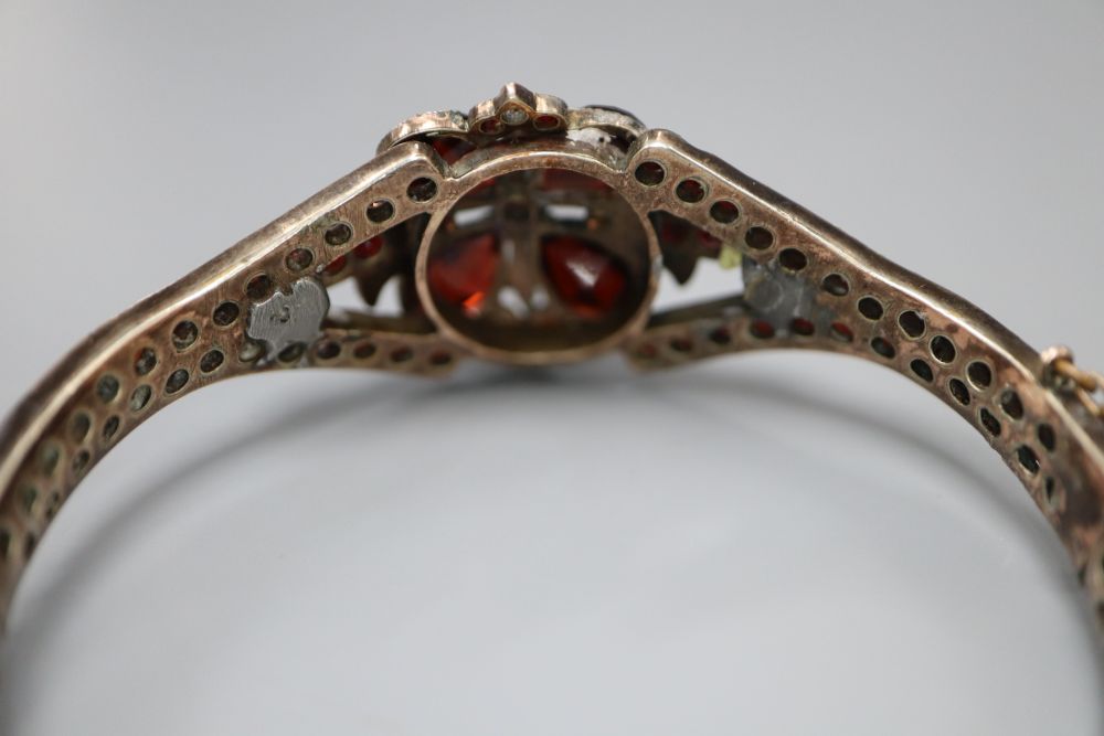 A Victorian gilt white metal and garnet set hinged bangle.